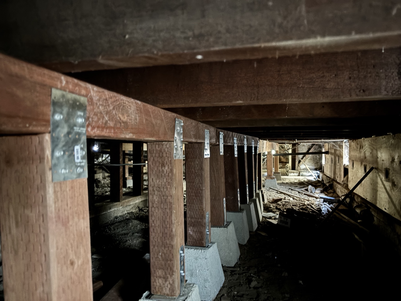 Close view of reinforced wooden posts and metal brackets under floor