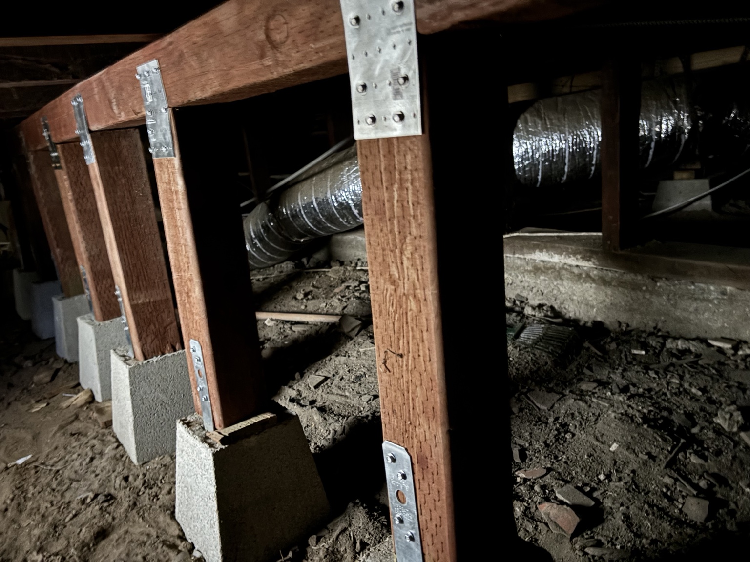 Reinforced beam with wood posts and metal connectors in crawl space