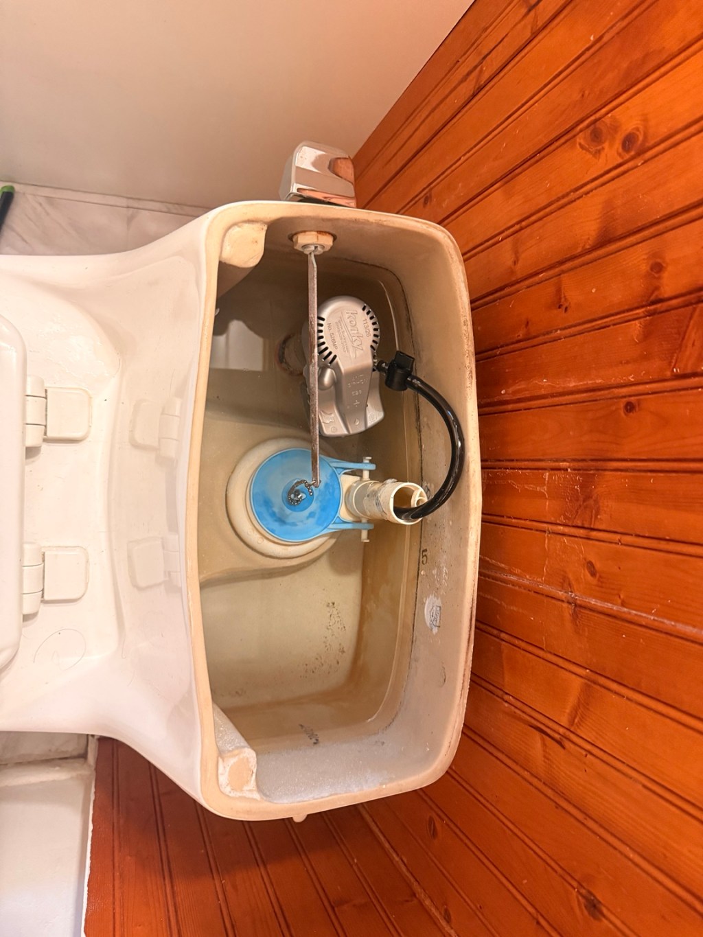 Inside a toilet tank during flush mechanism repair by ALEXKO LLC