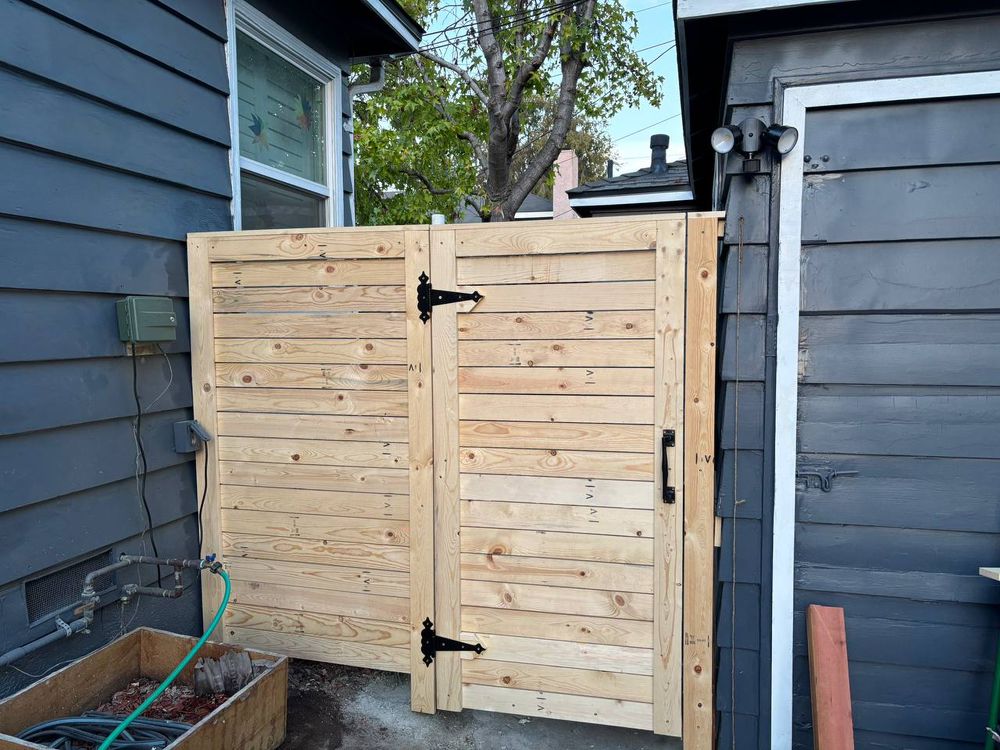 New horizontal-board wooden side gate with dark hinges and handle